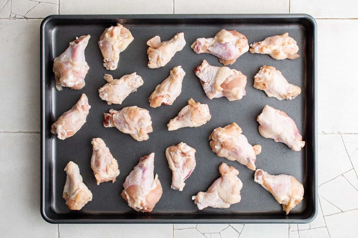 chicken drumettes arranged on a baking sheet.