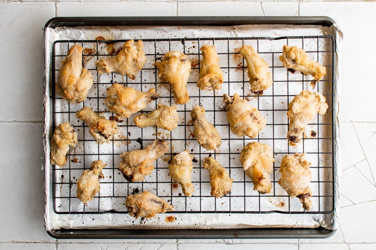 Crispy chicken wings on a baking rack over a baking sheet.