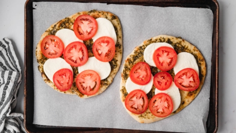 Flatbread with pesto, sliced tomatoes and sliced mozzarella cheese.