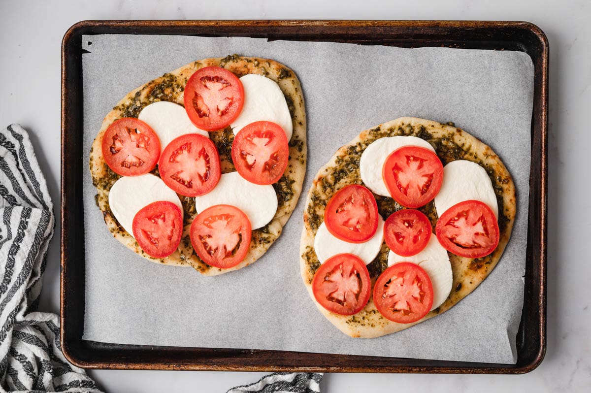 Flatbread with pesto, sliced tomatoes and sliced mozzarella cheese.