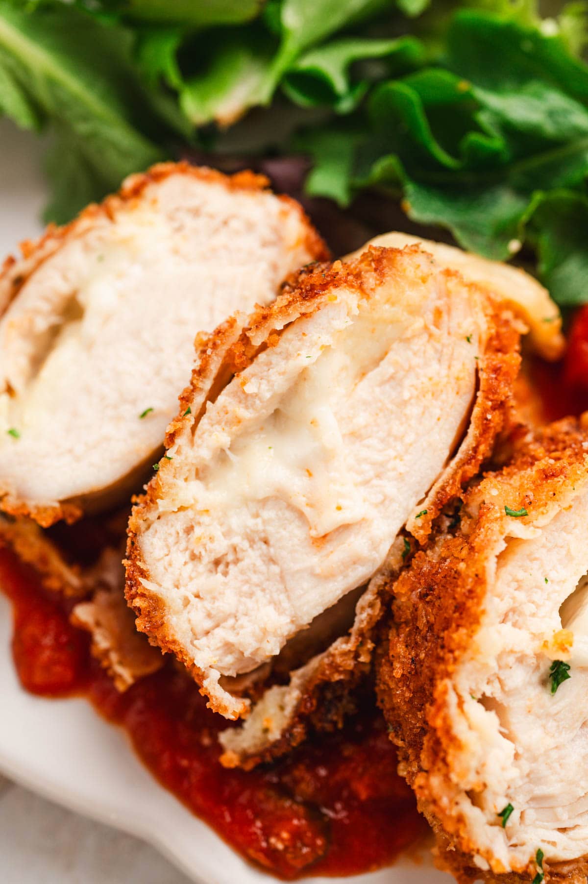 Mozzarella stuffed chicken breastwith crispy breading, sliced so you can see the mozzarella filling.