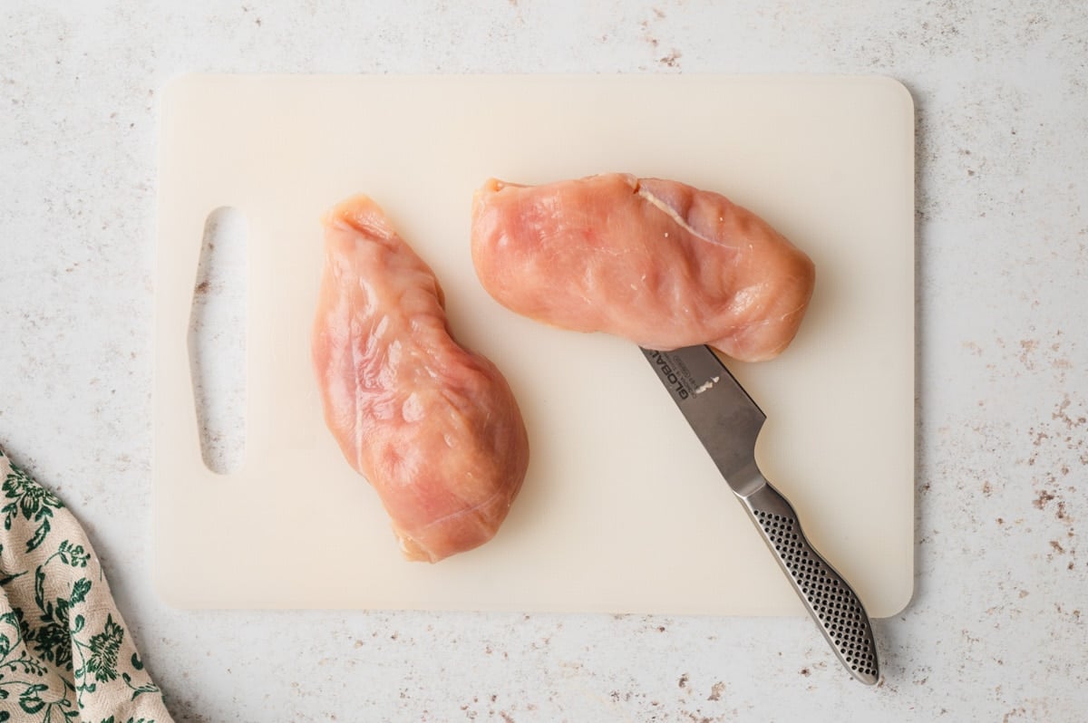 Raw chicken breasts with a large knife insterted.