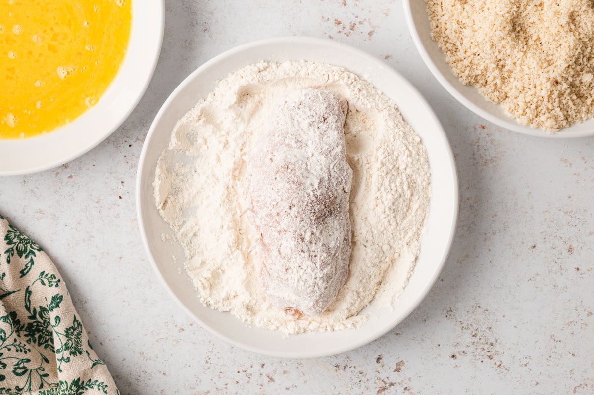 Chicken breast in a dish of flour.