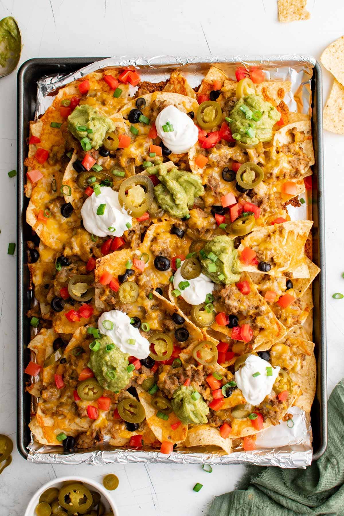 sheet pan nachos supreme with cheese, guacamole and sour cream