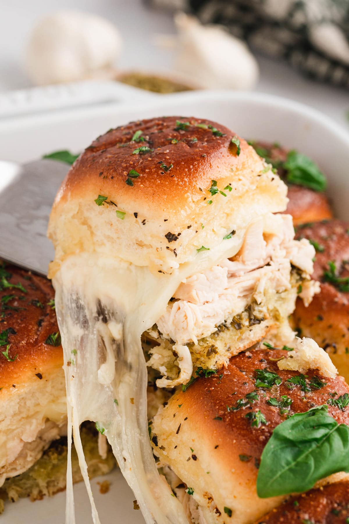 A pesto chicken slider picked up with a spatula.