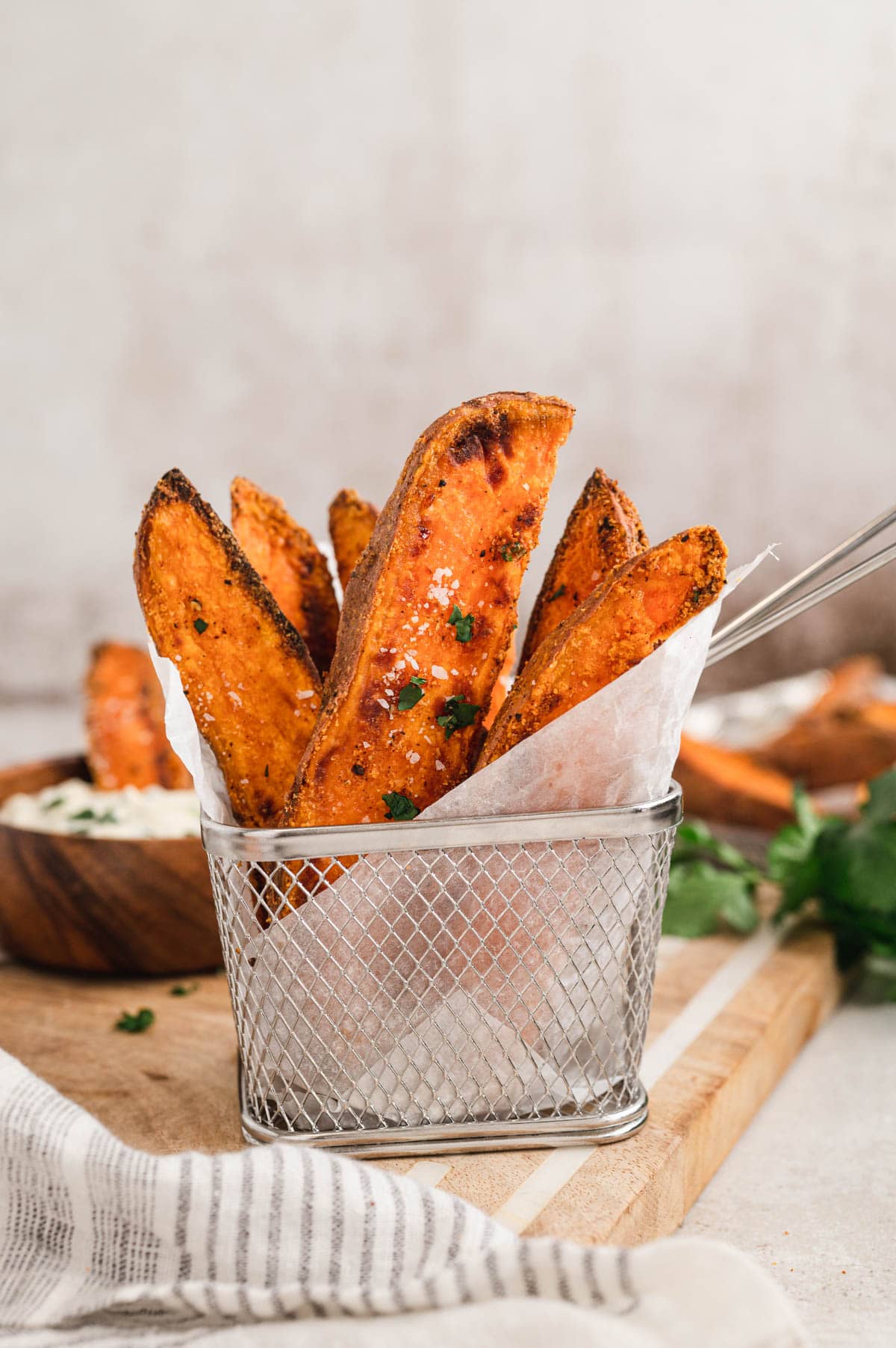 A small metal serving basket with sweet potato wedges standing upright.