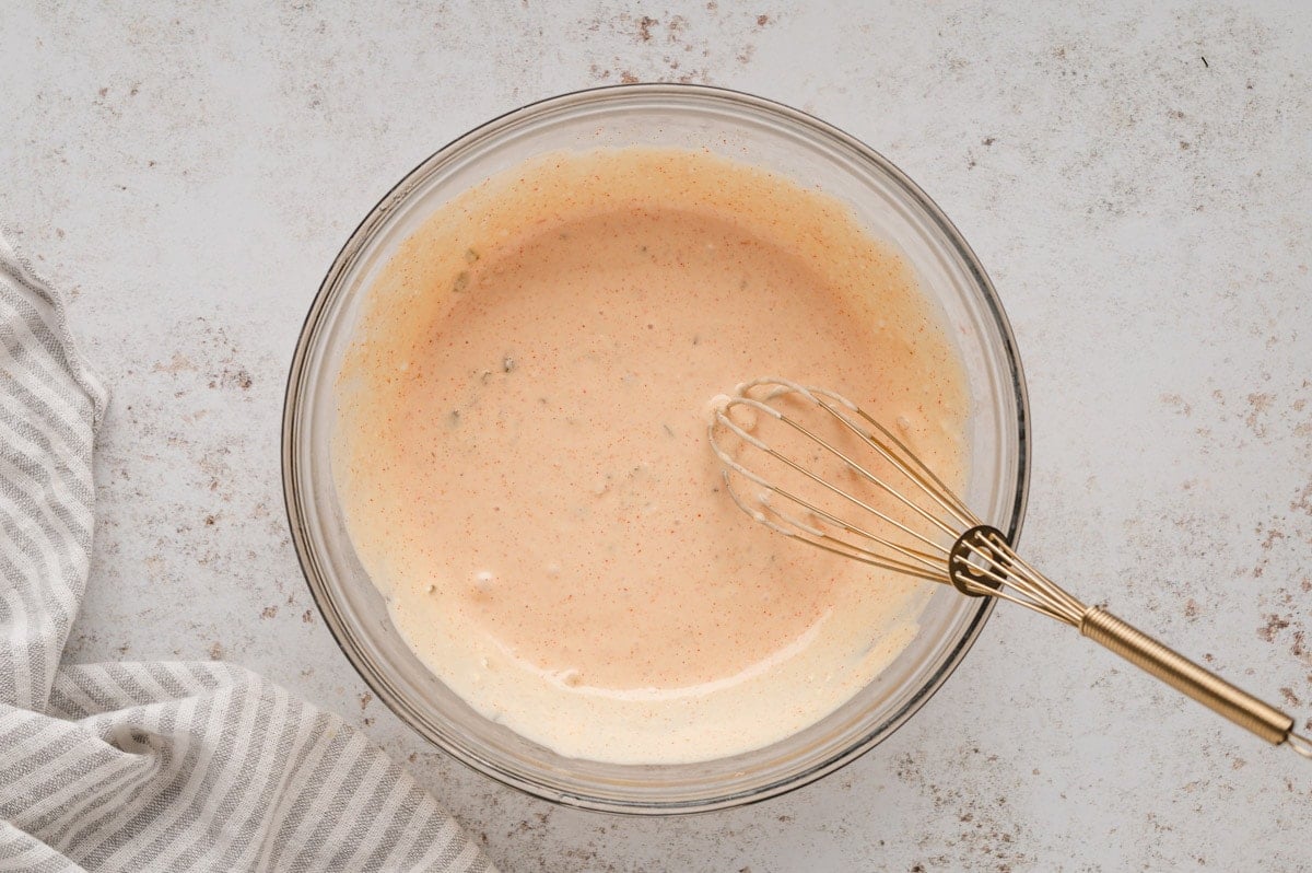 Big mac sauce mixed in a clear glass bowl with a small whisk.
