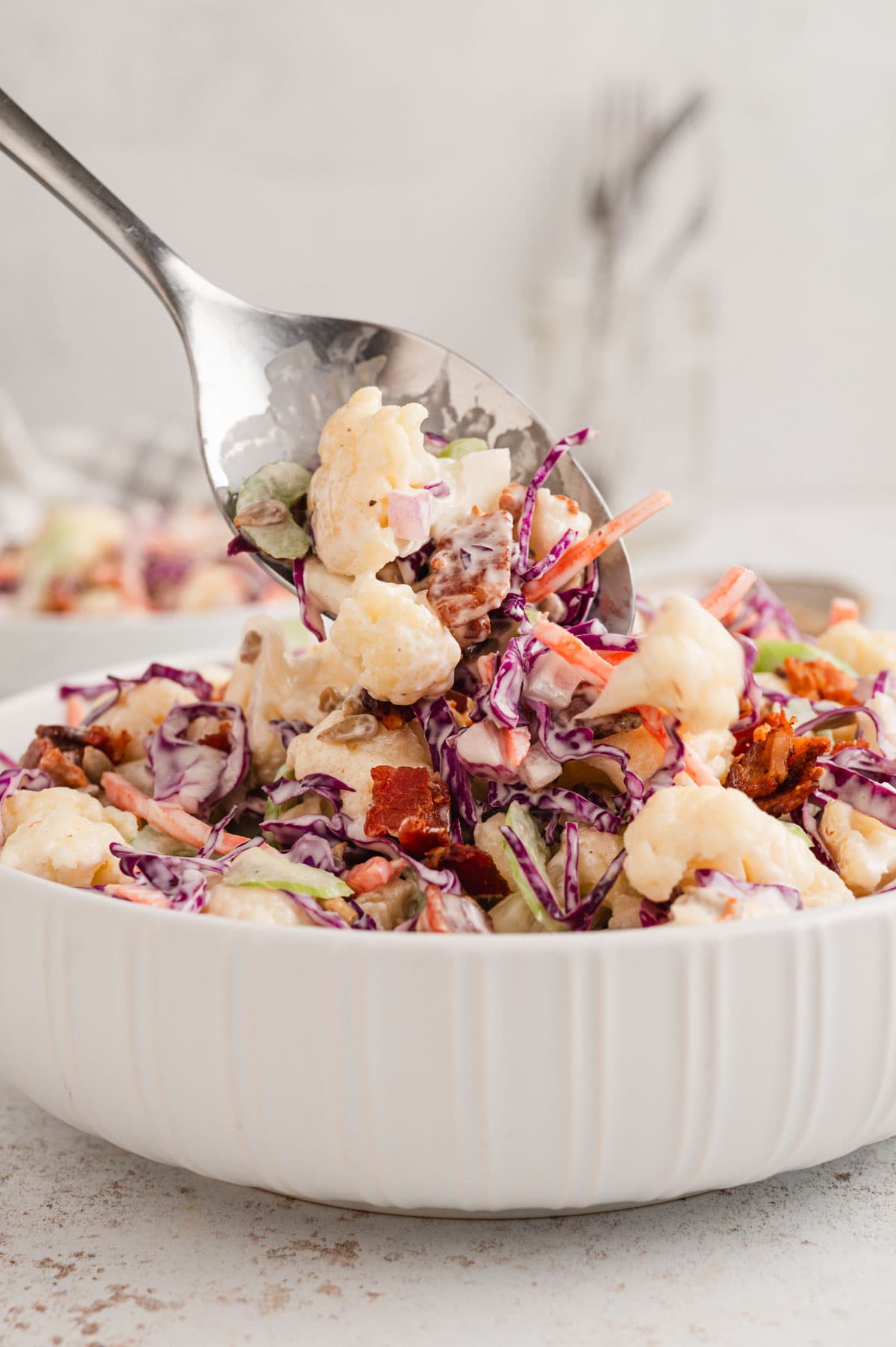 Spoon with cauliflower salad in a white dish.