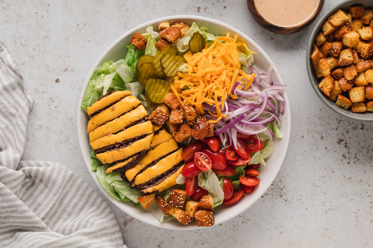 Salad with a cheeseburger patty, onions, tomatoes, croutons and pickles.