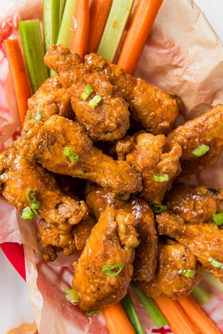 Basket of buffalo wings and carrot and celery sticks.