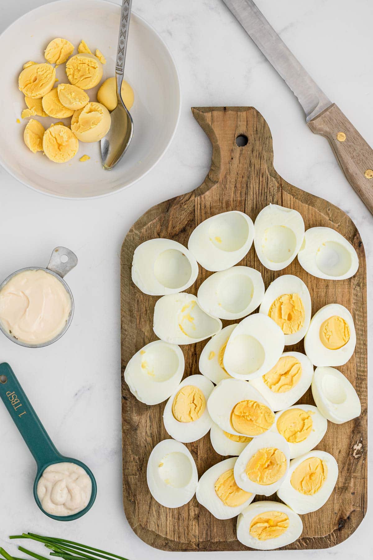 hard boiled eggs on a cutting board, sliced, and yolks in a bowl