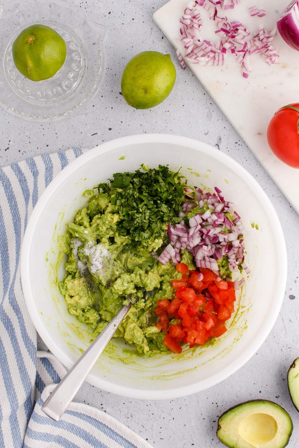 Bowl of mashed avocado, diced tomato, chopped cilantro and diced onion.