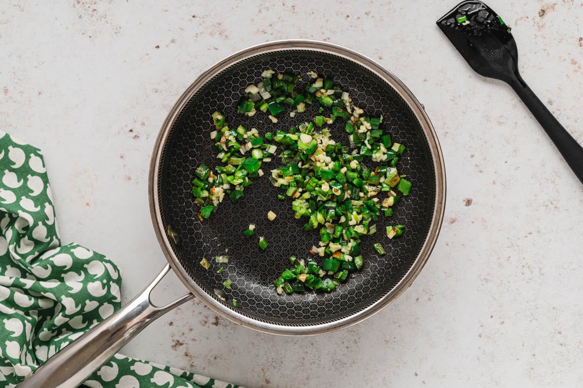 Dice jalapenos and green onions in a skillet.