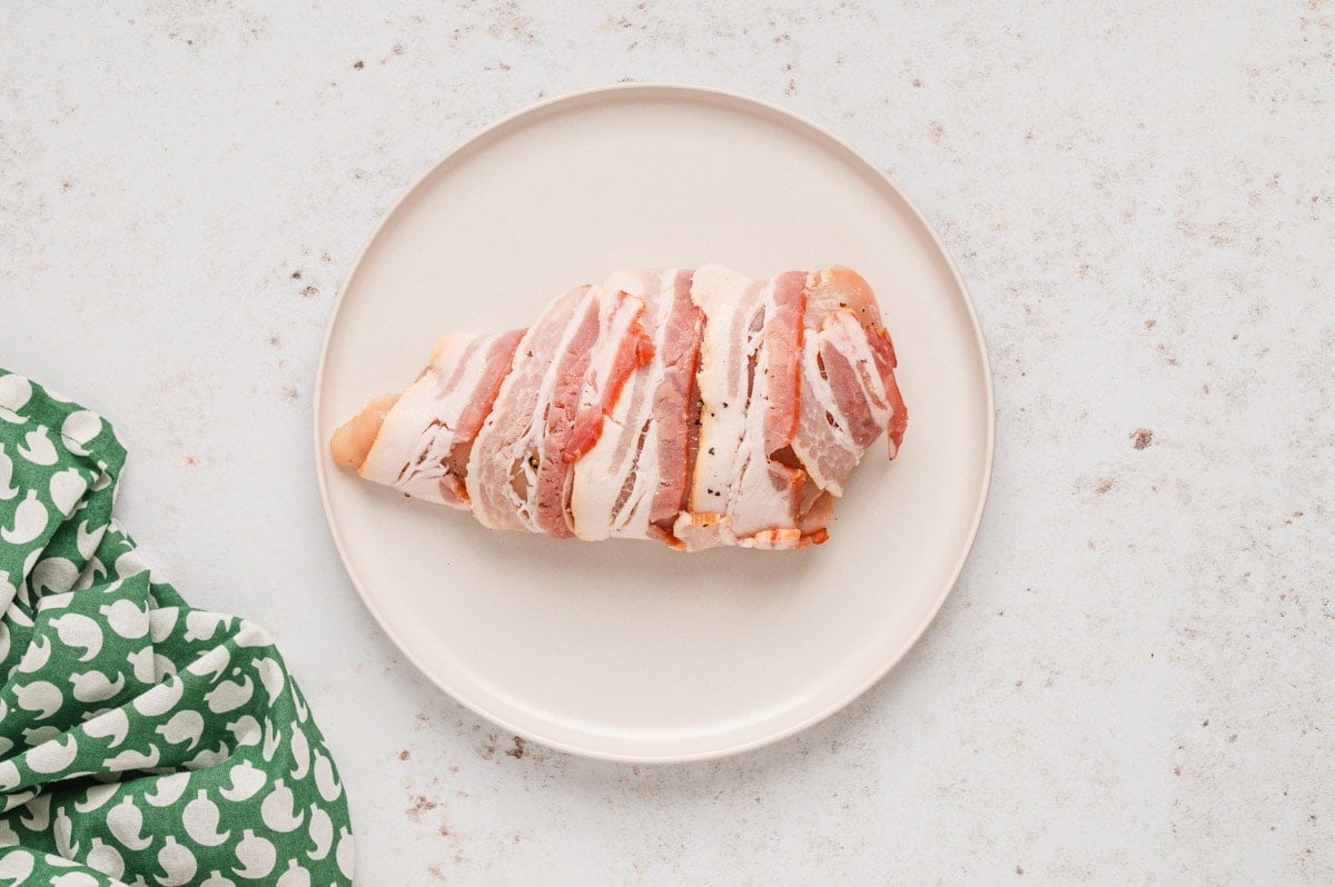 Raw chicken breast wrapped in raw bacon.