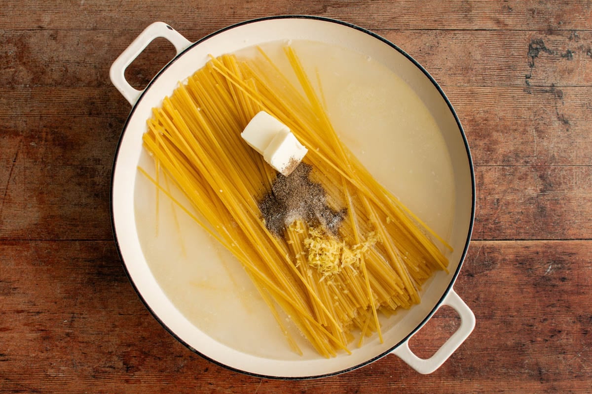 Uncooked linguine noodles, butter, lemon zest, water and pepper in a large skillet.