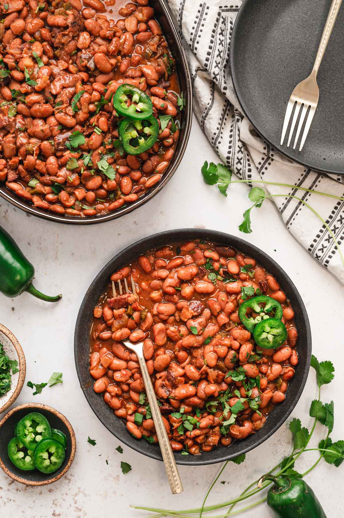 A bowl of Mexican beans topped with jalapeno slices.