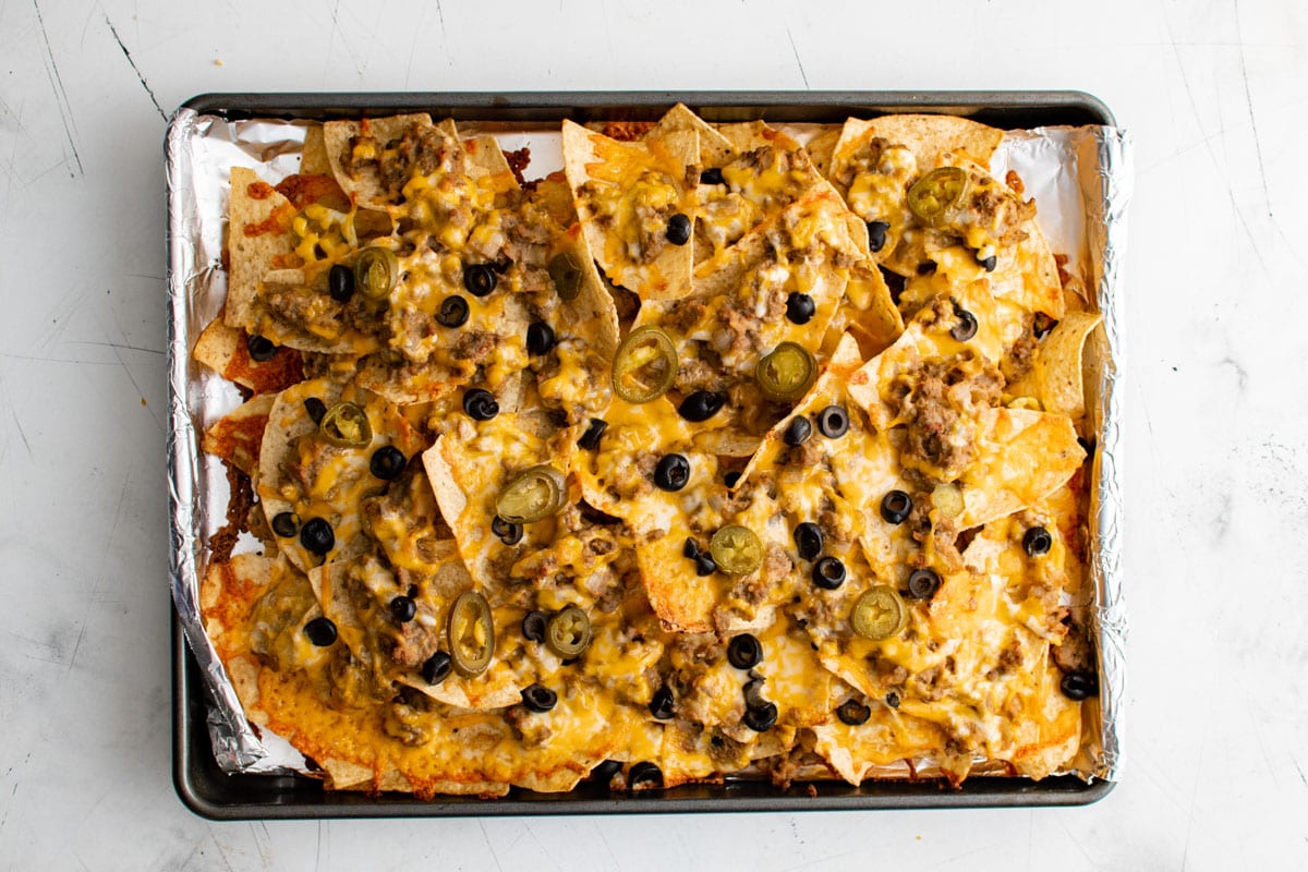 Baked nachos supreme on a foil lined sheet pan.