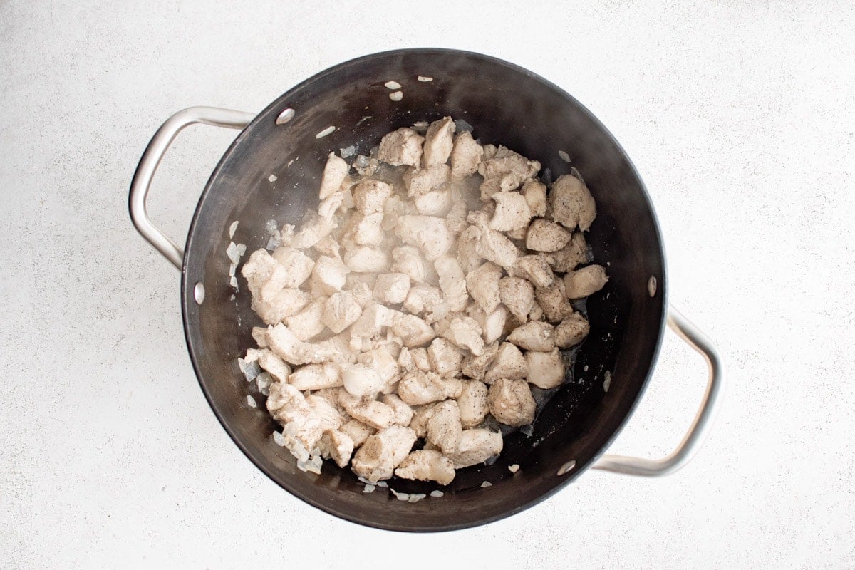 Chicken pieces cooking in a large pot.