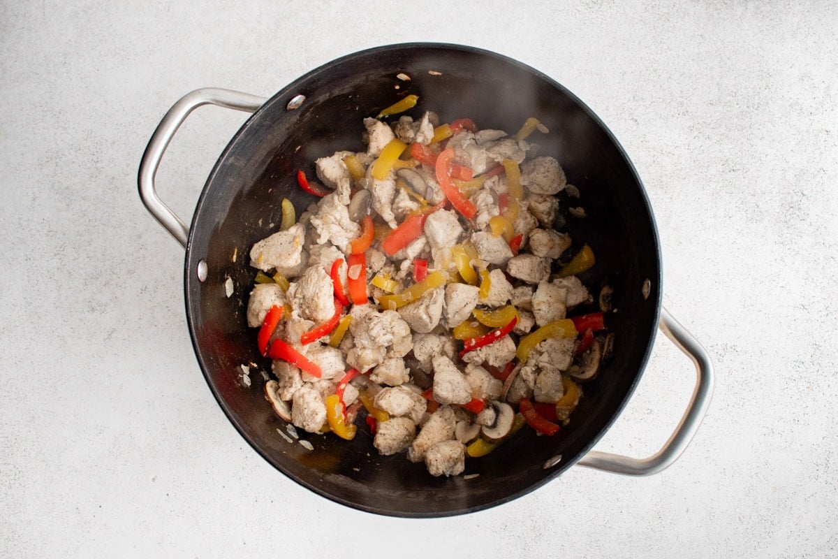 Chicken and veggies cooking in a pan.