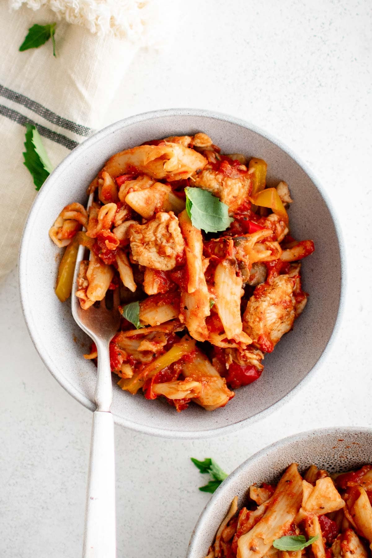 Bowl with chicken, pasta and red sauce and a fork.