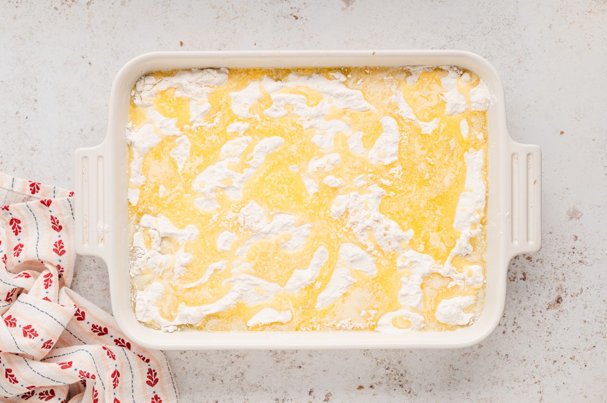 White baking dish, cake mix sprinkled all around, melted butter on top.