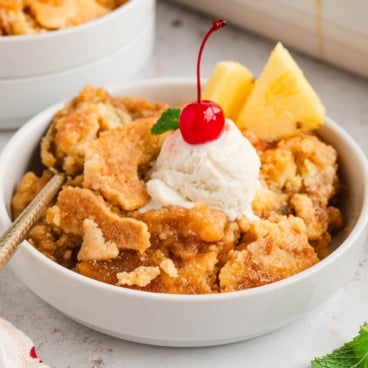 pineapple dump cake in a bowl with ice cream