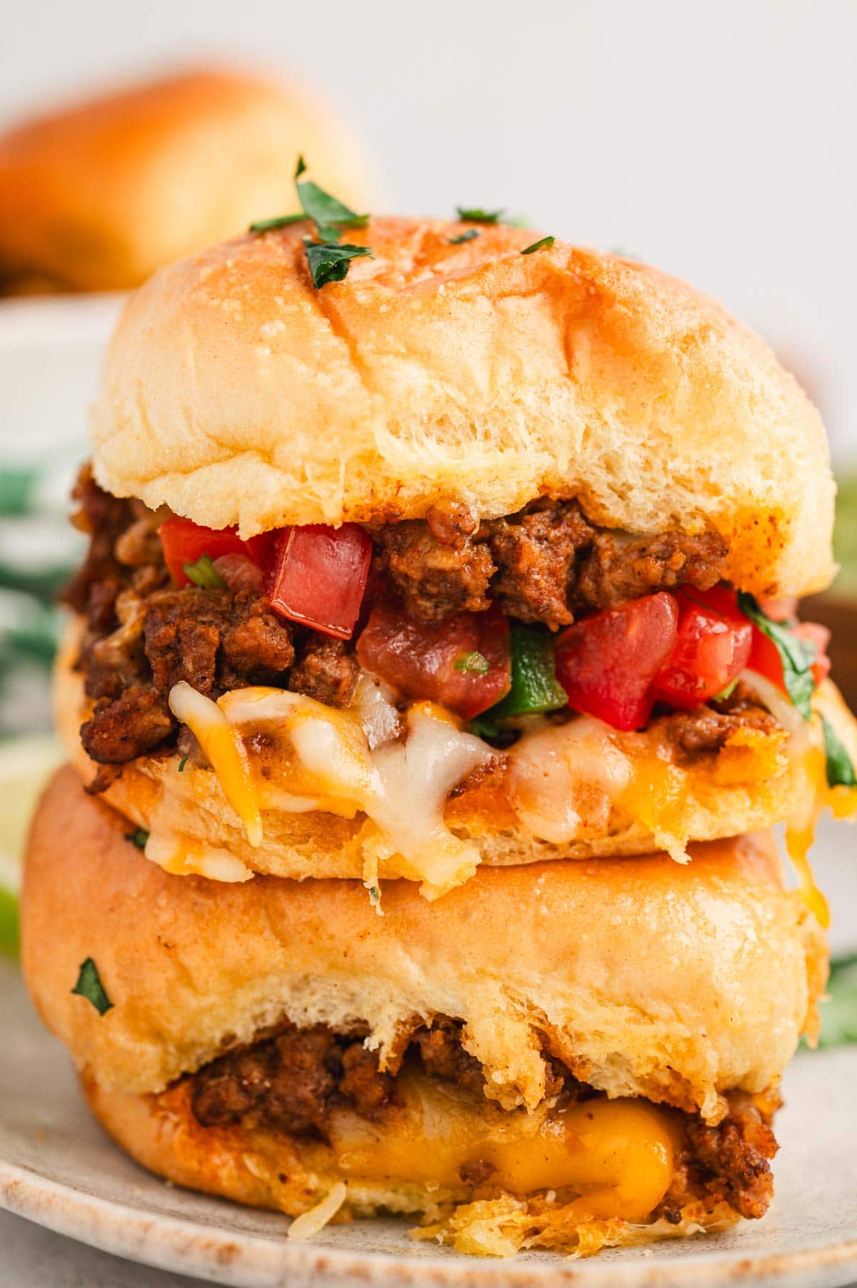Two sliders stacked on top of each other, filled with taco meat and pico de gallo.
