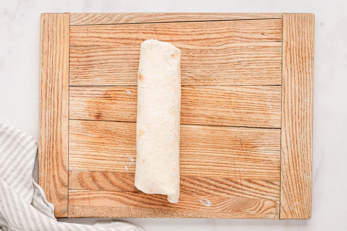 Rolled up tortilla on a cutting board.