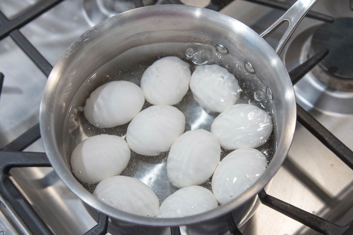 Eggs simmering in a pan of water.