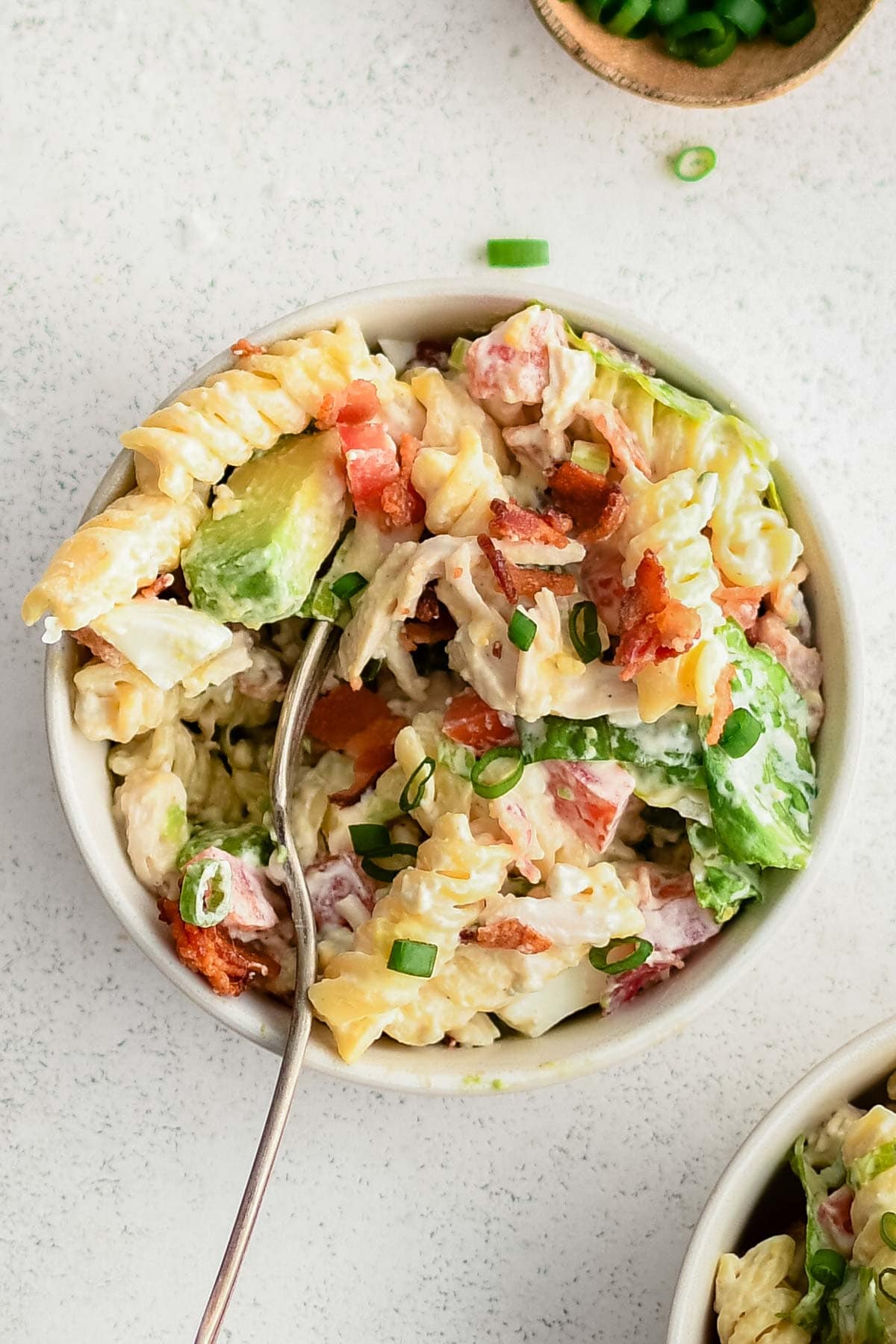 A small bowl with a serving of cobb pasta salad.