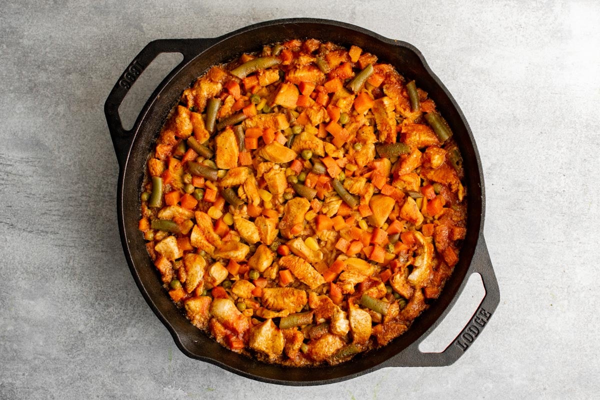 Cooked chicken, vegetables and rice in a cast iron skillet. 