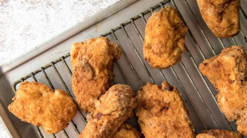 Breaded and fried chicken pieces on a wire rack.