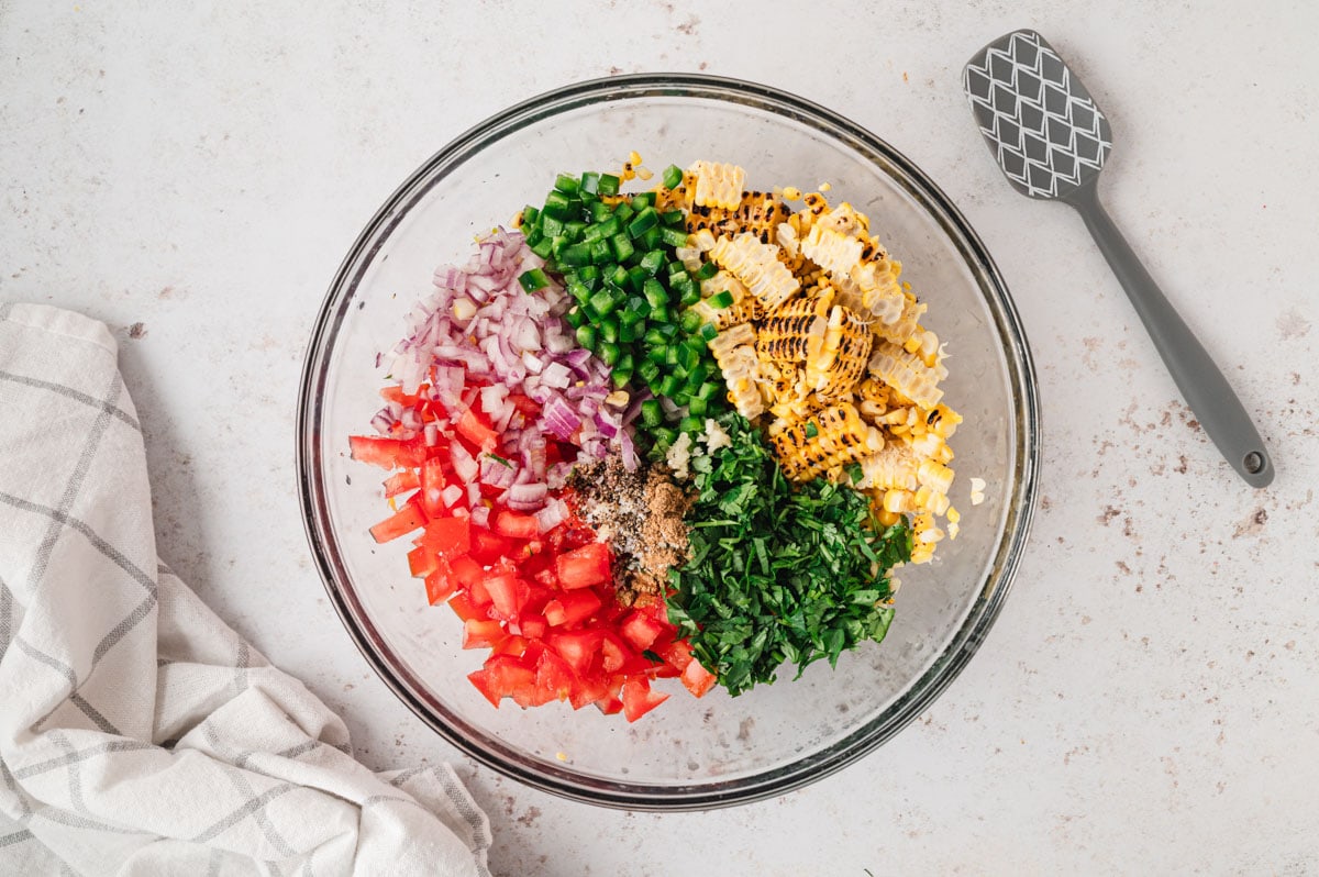 Corn, diced jalapeno, diced tomato and diced onion in a bowl.