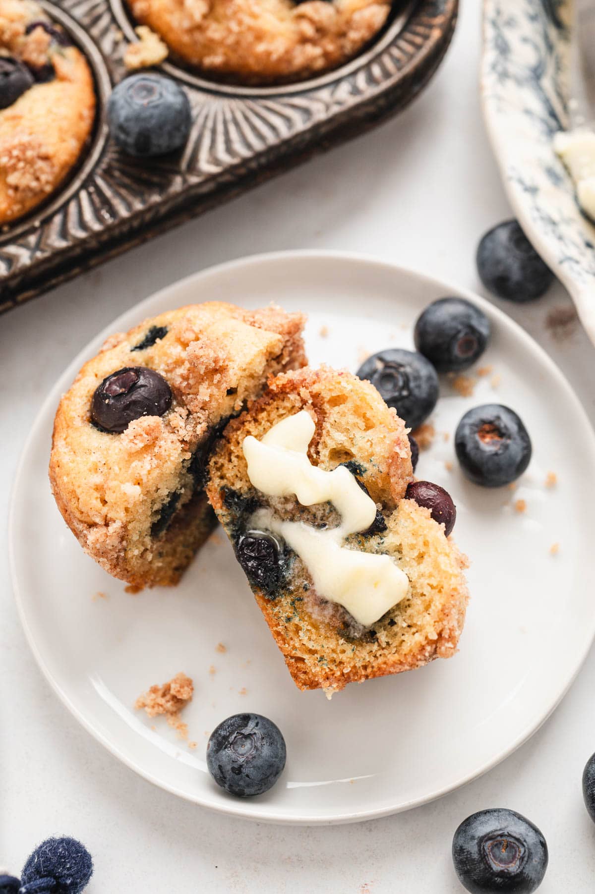 Blueberry muffin sliced in half with butter.