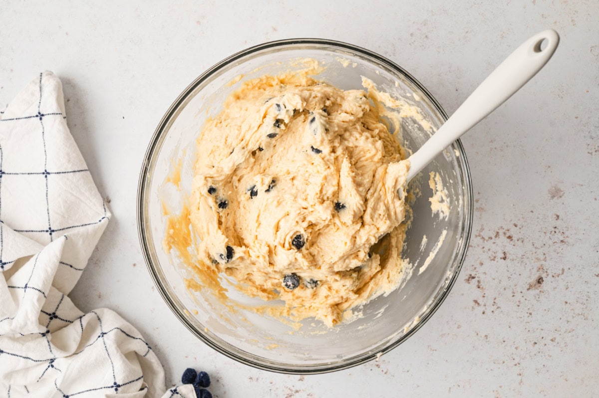 Bluenerry muffin batter in a bowl with a hand mixer.