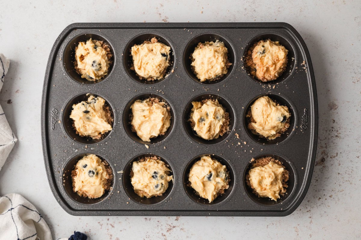 Blueberry muffin batter in a muffin pan.