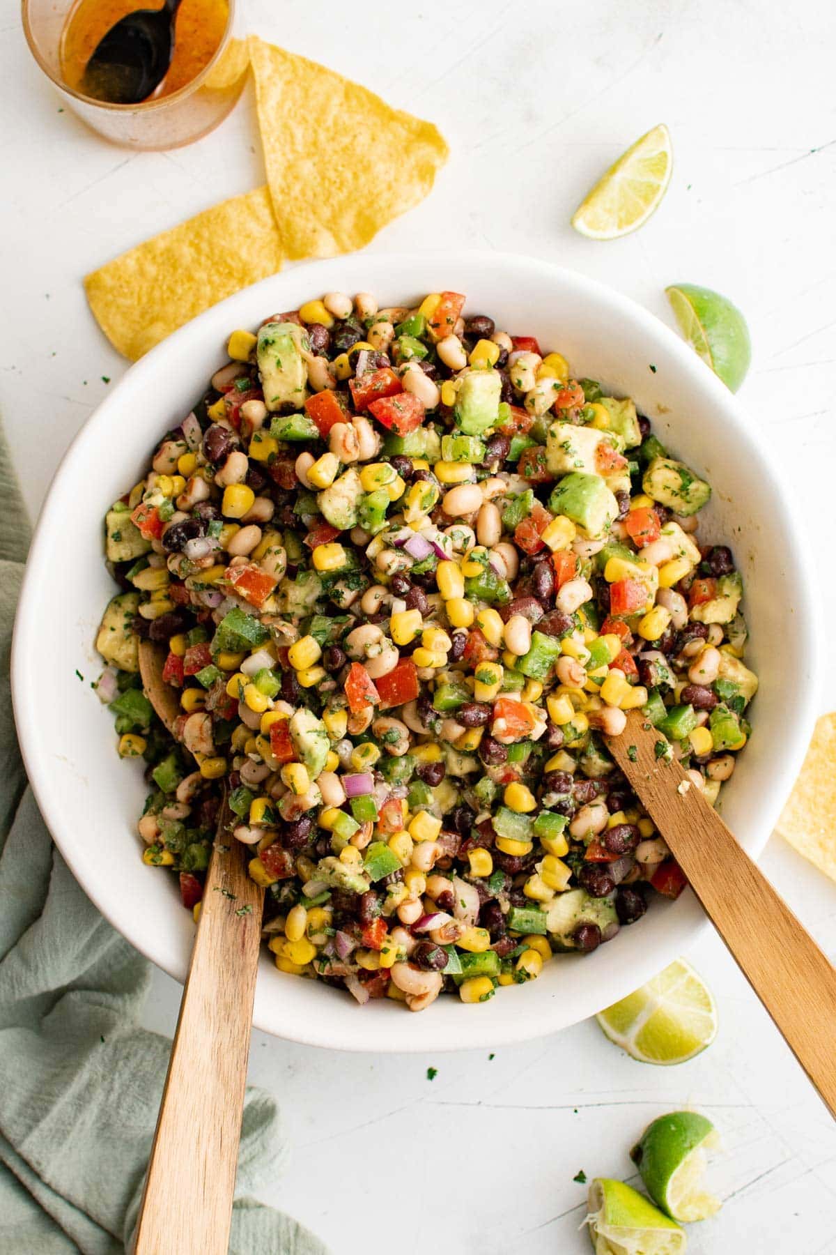White bowl with cowboy caviar and two wooden spoons. 