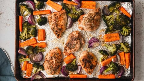 Baked chicken broccoli and carrots on a sheet pan.