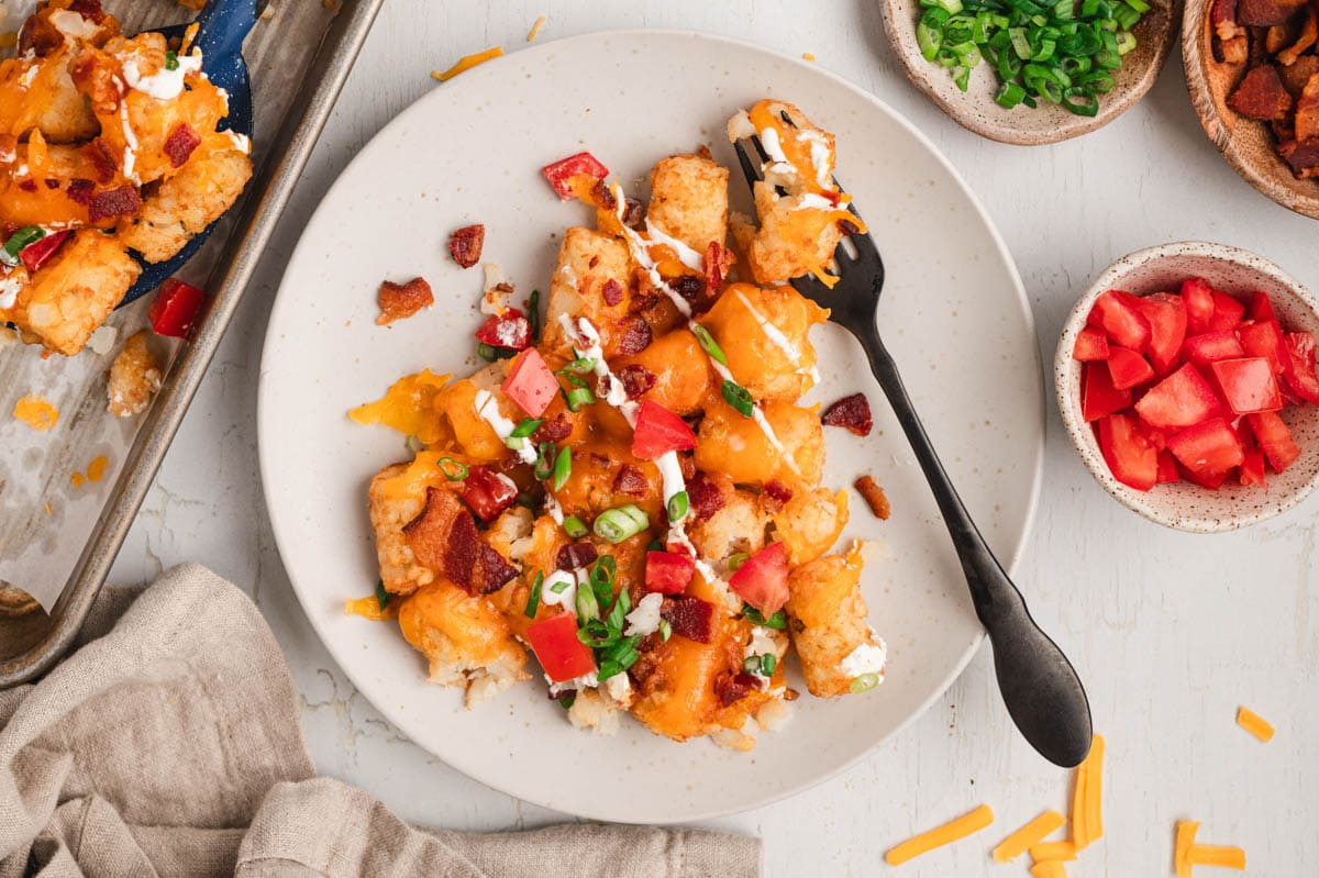 tater to nachos on a plate with a black fork.