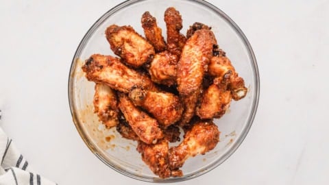 baked chicken wings in a glass bowl with marinade sauce.