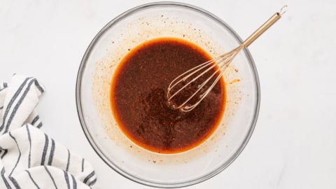 Marinade in a glass bowl with a whisk.