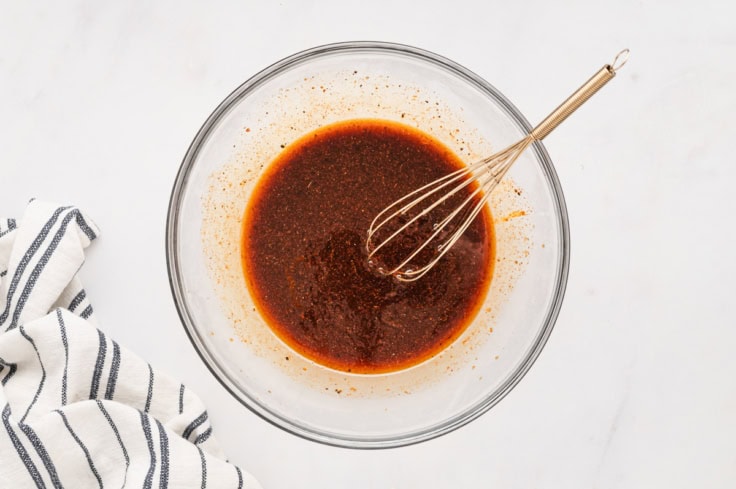Marinade in a glass bowl with a whisk.