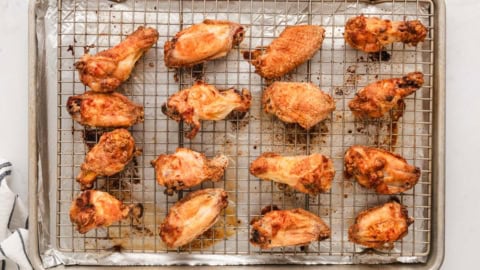baked chicken wings on a wire rack over a baking sheet.