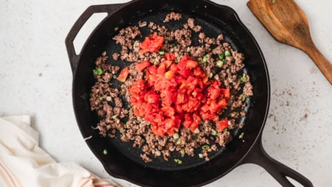 ground beef and tomatoes in a cast iron skillet.