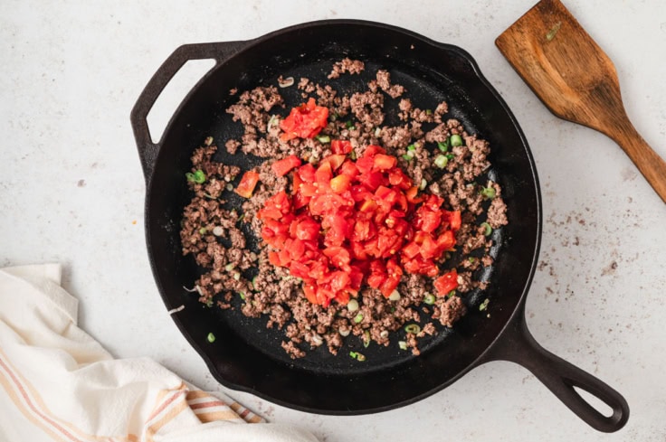 ground beef and tomatoes in a cast iron skillet.