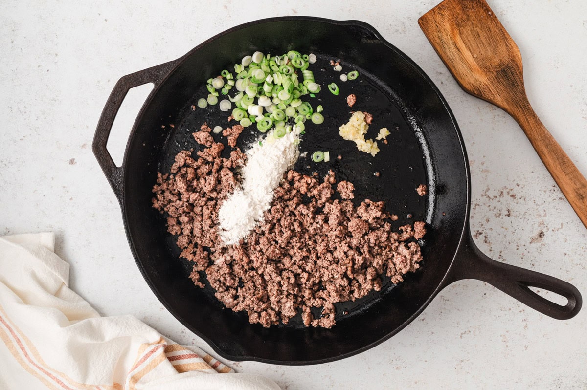 ground beef, sliced green onions and flour in a skillet.