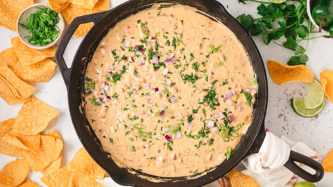 Chili con quesa in a skillet surrounded by tortilla chips.