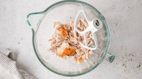 Stand mixer with a bowl of shredded chicken.