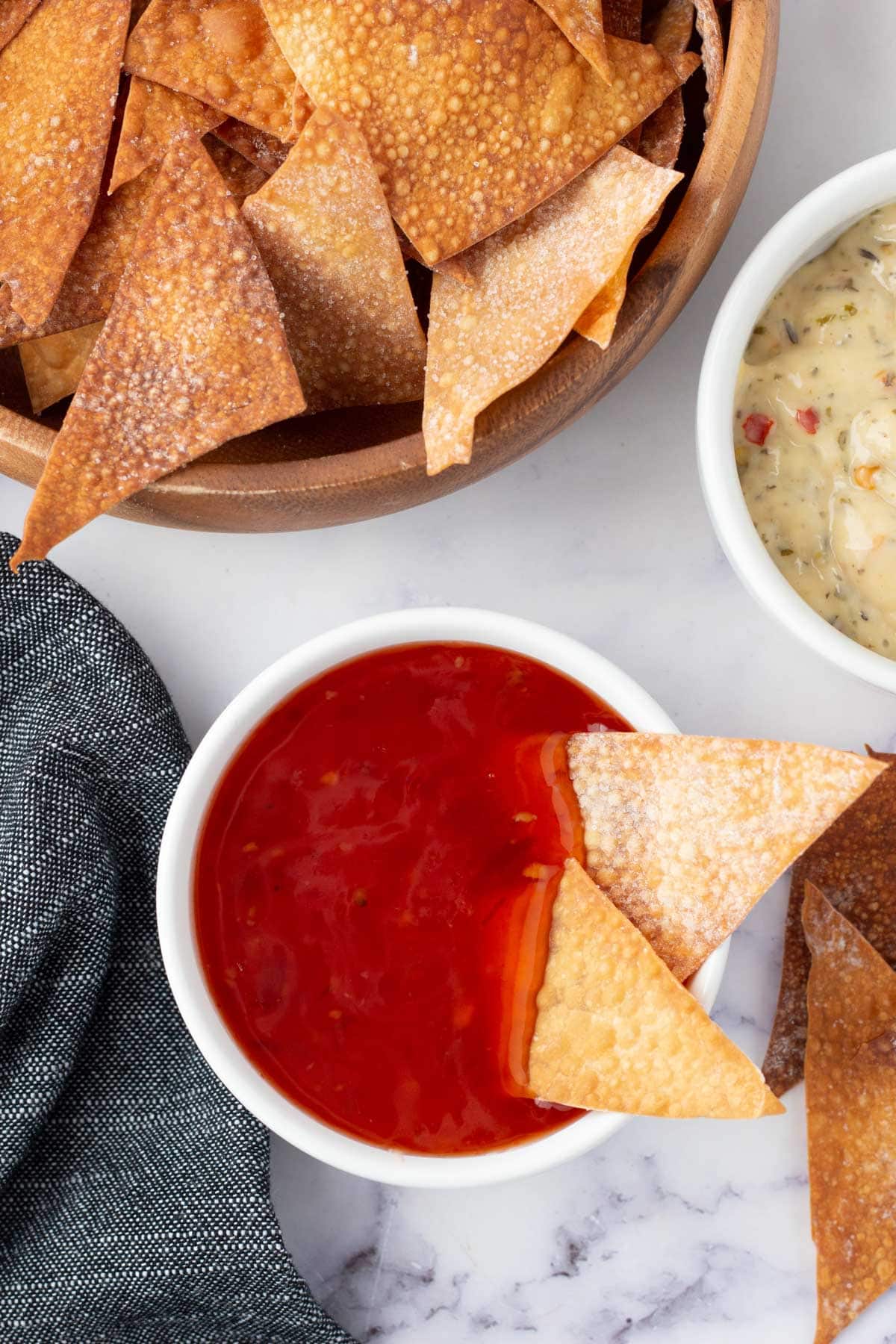 Wonton chips in a bowl, and 2 in a dish of sweet and sour sauce.