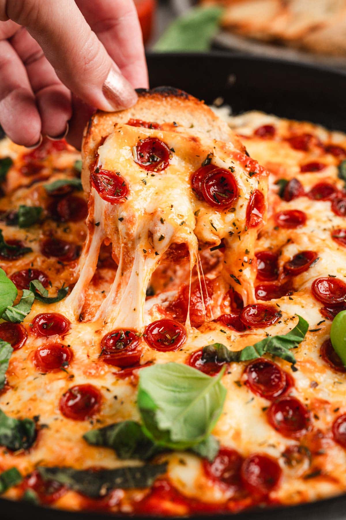 Close up of crostini dipped in melty pizza dip.